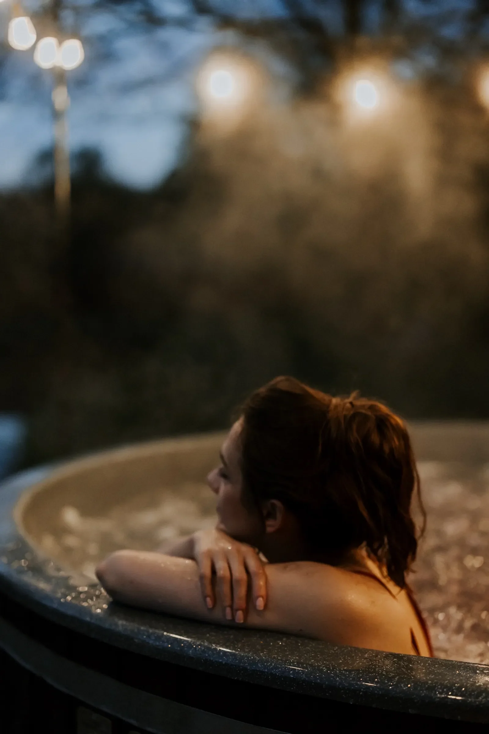 Kobieta odpoczywająca na krawędzi balii z jacuzzi o zmierzchu
