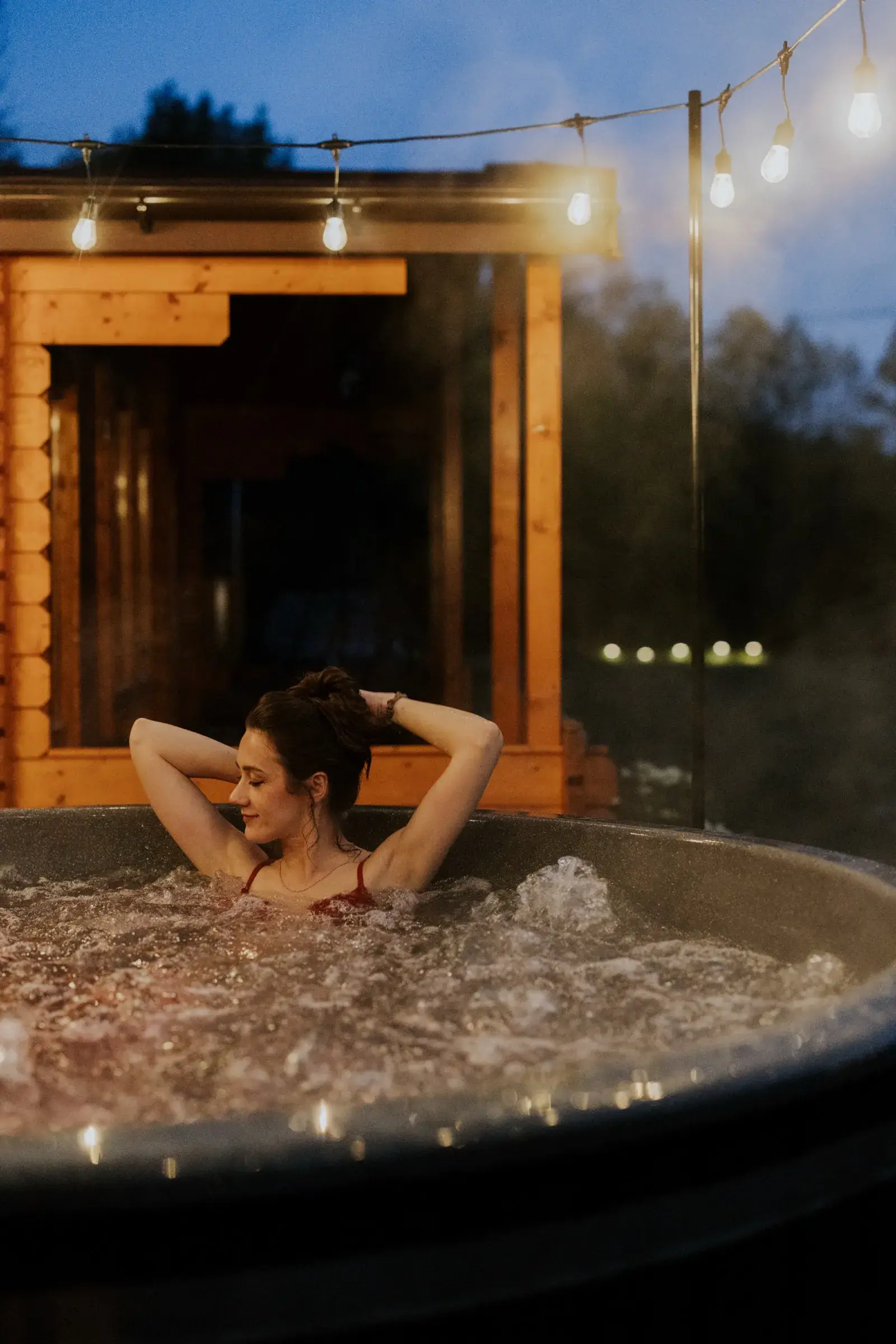 Prywatna balia z jacuzzi na tarasie domku, para relaksująca się wieczorem
