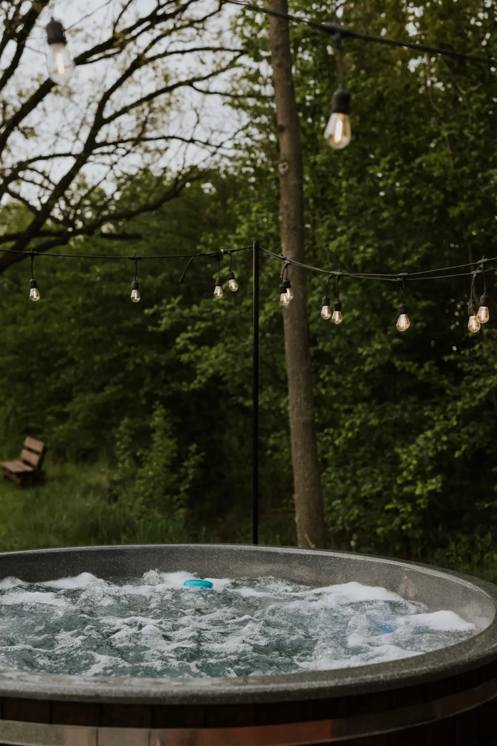 Balia z jacuzzi pełna piany o zmierzchu, girlandy nad tarasem