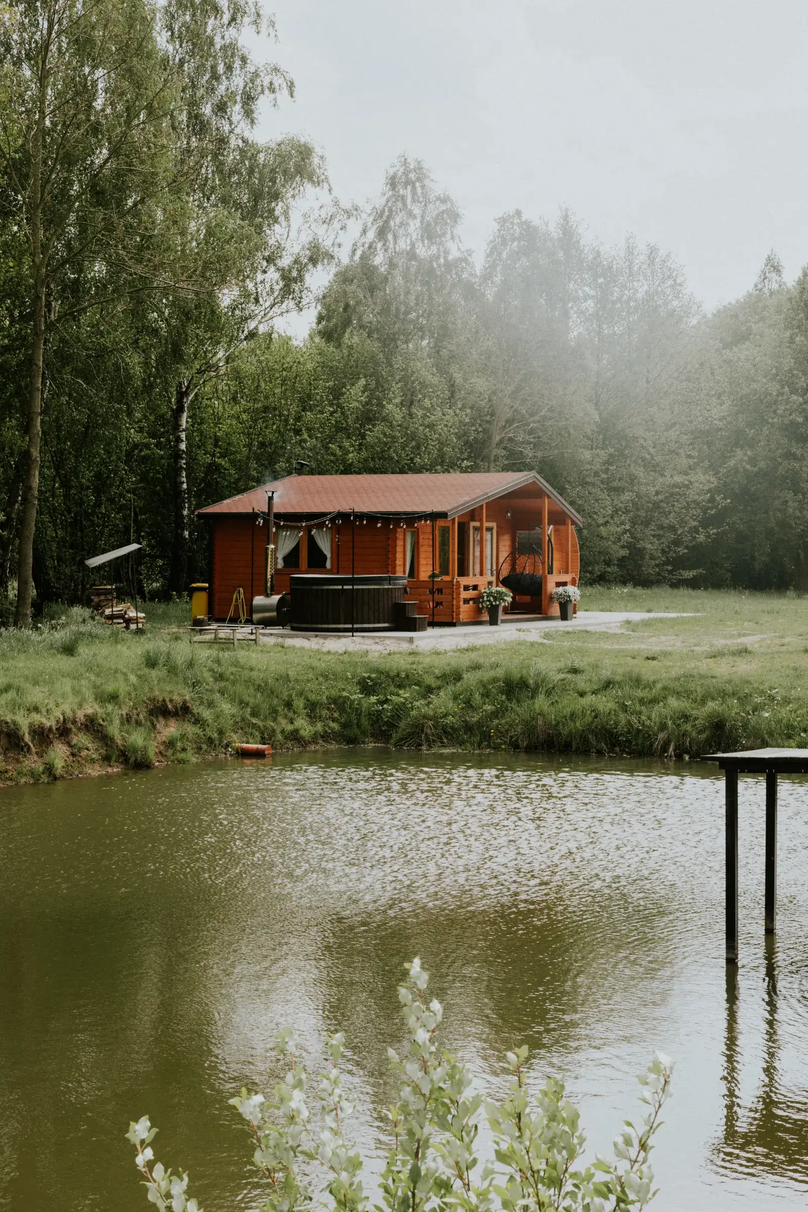 Domek nad zarybionym stawem o poranku, mgła nad wodą i pomost